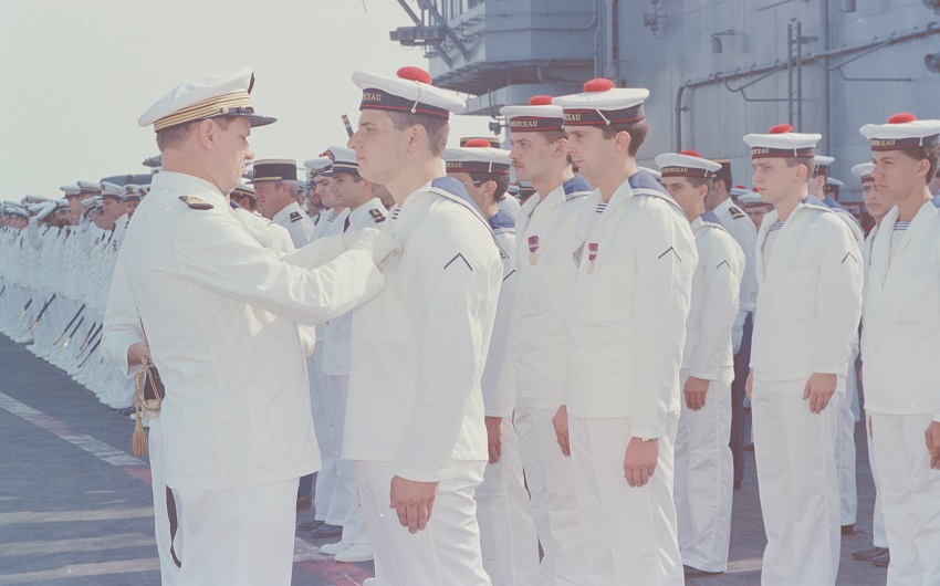 Au moment où il quitte le commandement du Clemenceau, le capitaine de vaisseau Lefebvre décore les appelés du contingent de la médaille de la Défense nationale. A la fin des années 1980, tant sur le Foch que sur le Clemenceau, de nombreux marins de l’équipage sont des appelés du contingent. Par exemple, les conducteurs et le personnel de pont d’envol (CONEV et PONEV) le sont tous à l’époque. ©Philippe LECOMTE/ECPAD/Défense